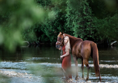 horse and lady standing in a river. equine photographer